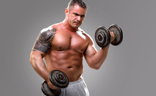 Bodybuilder with a tattoo lifting dumbells, closeup